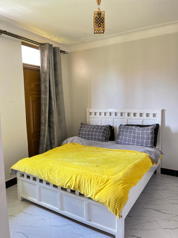 ein Schlafzimmer mit einem weißen Bett und einer gelben Decke in der Unterkunft P&P homes in Kampala
