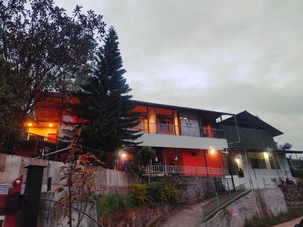 uma casa com portas vermelhas e uma árvore na frente dela em Soul Stay em Munnar
