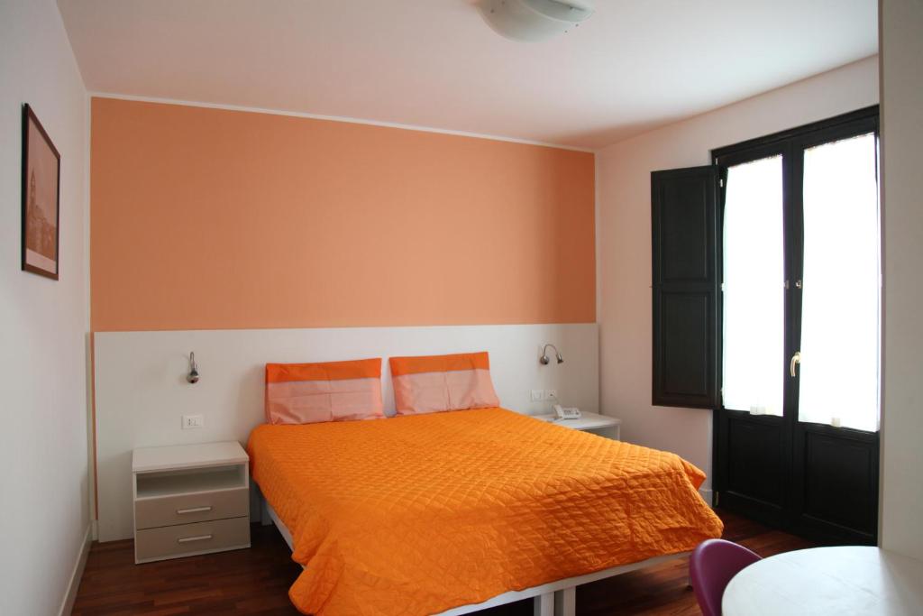 パラッツォーロ・アクレイデにあるRTA Palazzo Judicaのベッドルーム1室(オレンジ色のベッド1台、窓付)