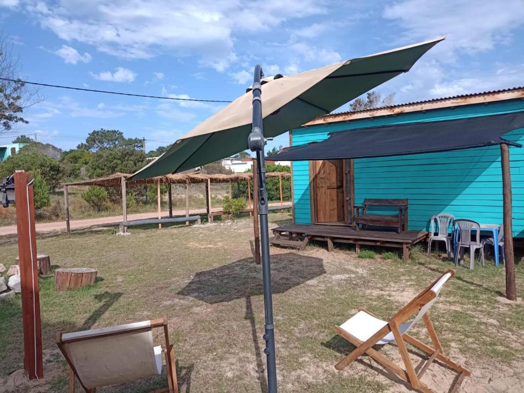 a blue house with a blue umbrella in front of it at Cabaña Fran in Punta Del Diablo