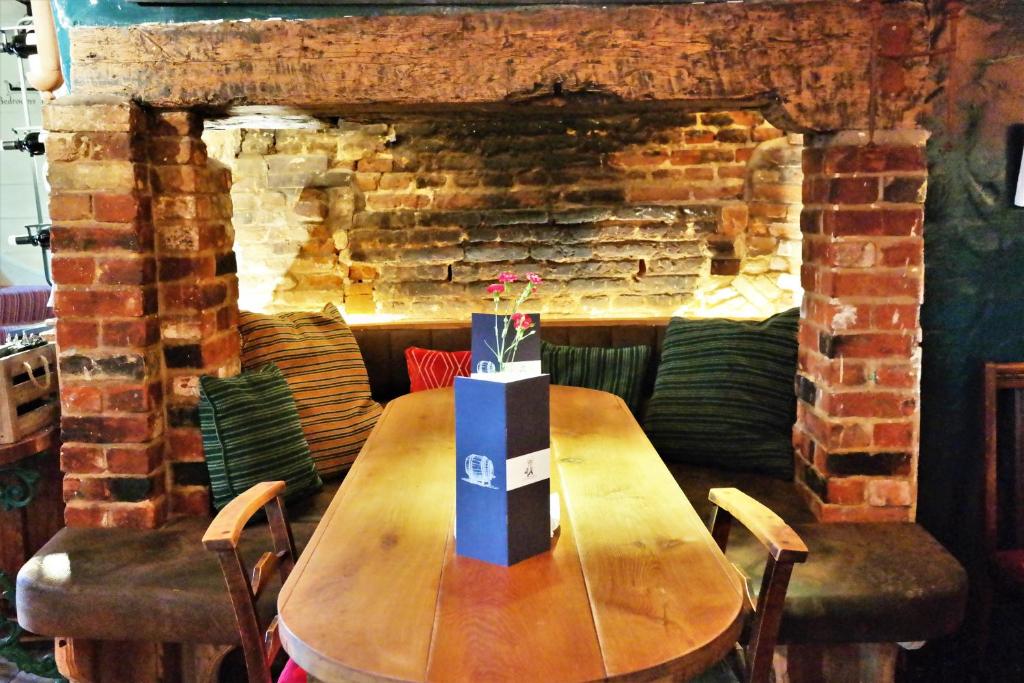 una mesa de madera en una habitación con una pared de ladrillo en The Cross Keys, en Saffron Walden