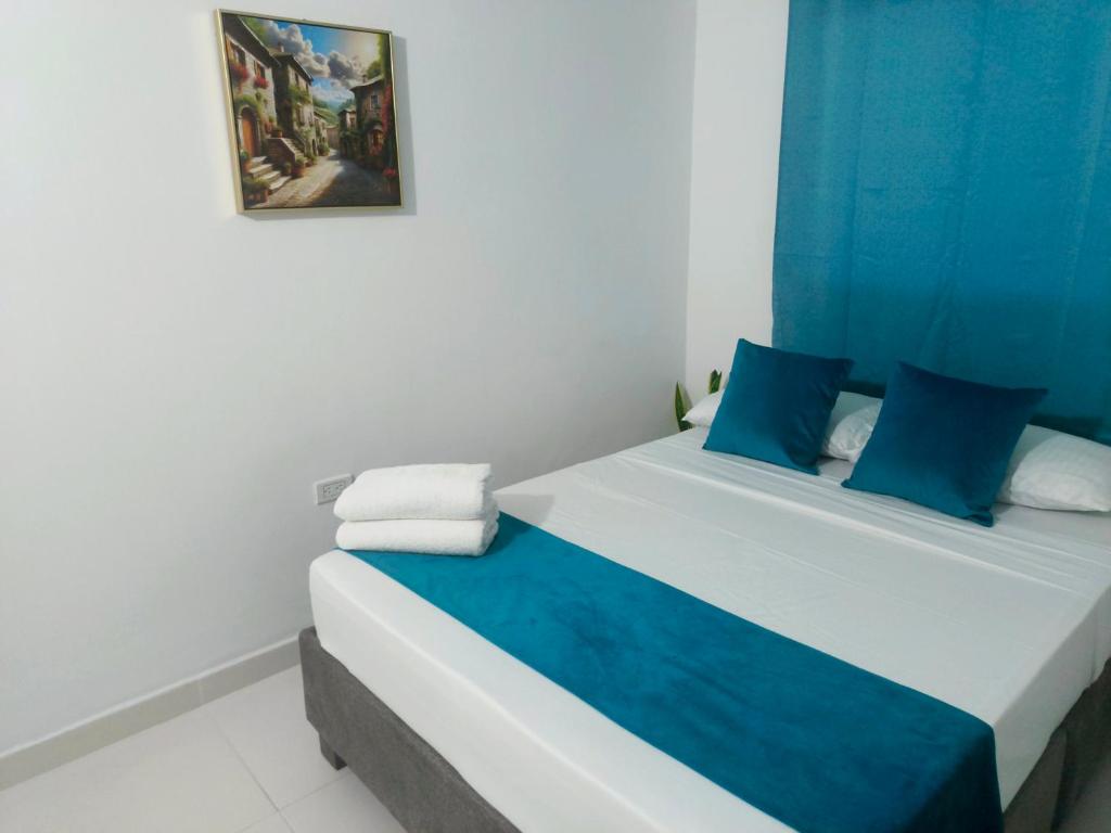 a bedroom with a bed with blue and white pillows at Hospedaje Torices Cartagena in Cartagena de Indias