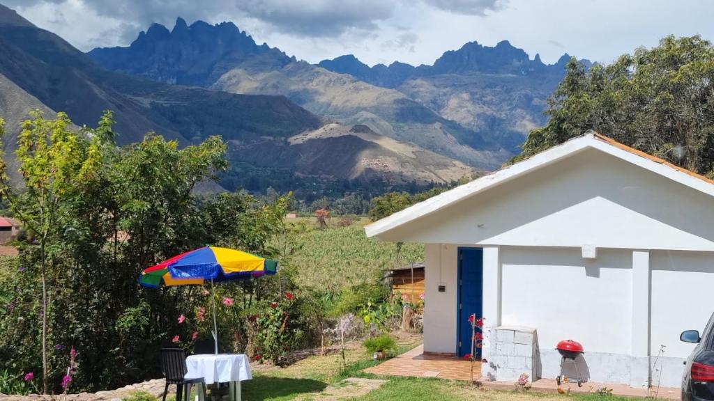 a colorful umbrella in front of a building with mountains at Cottage in nature in Sacred Valley with mountain views in Huayllabamba