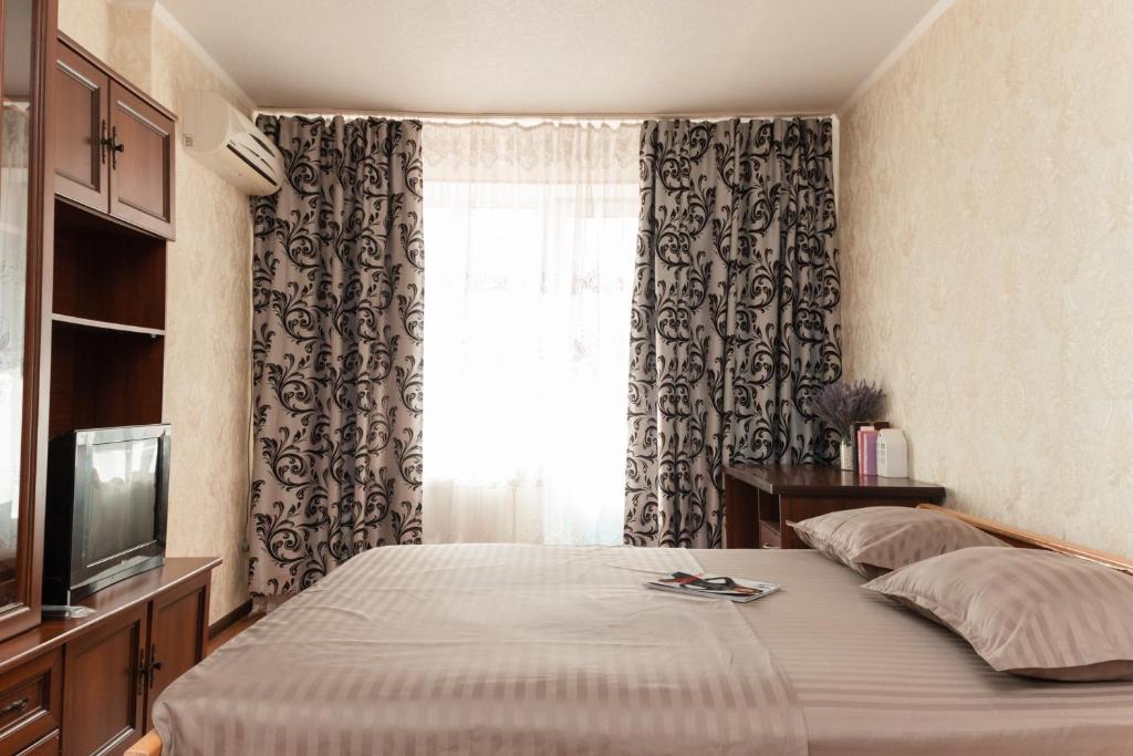 Un dormitorio con una cama con televisión y una ventana. en Luxury 1-bd Apartment Novomestenska Street, en Sumy