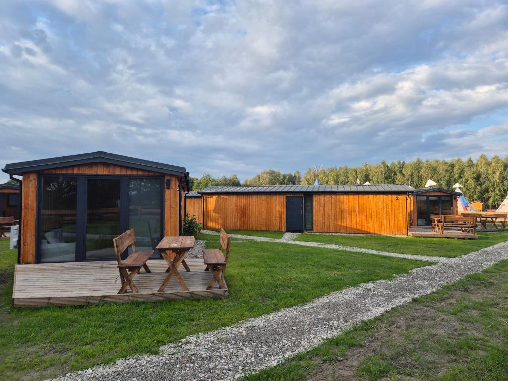 GrabceZacisze obok Suntago Park domki 2,3,6 osobowe的草地上有一间小屋，里面有两把椅子和一张野餐桌