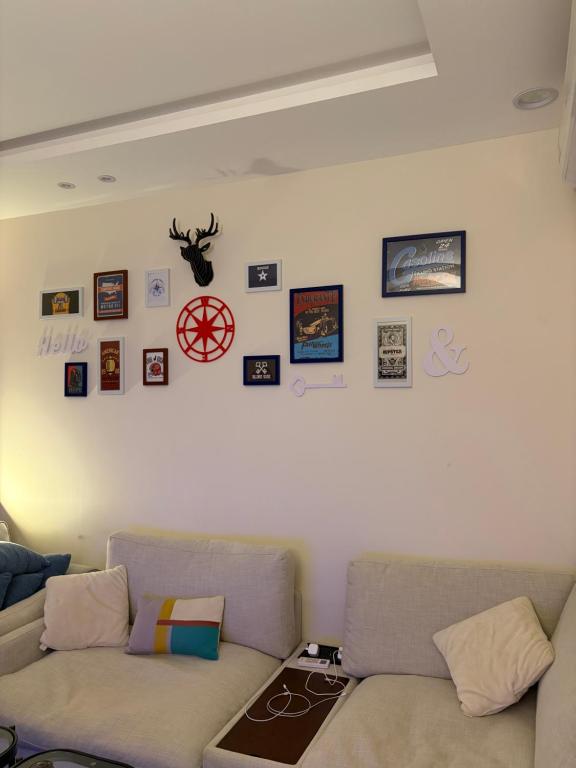 a living room with two couches and pictures on the wall at Friendly apartment with friendly pet in Riyadh