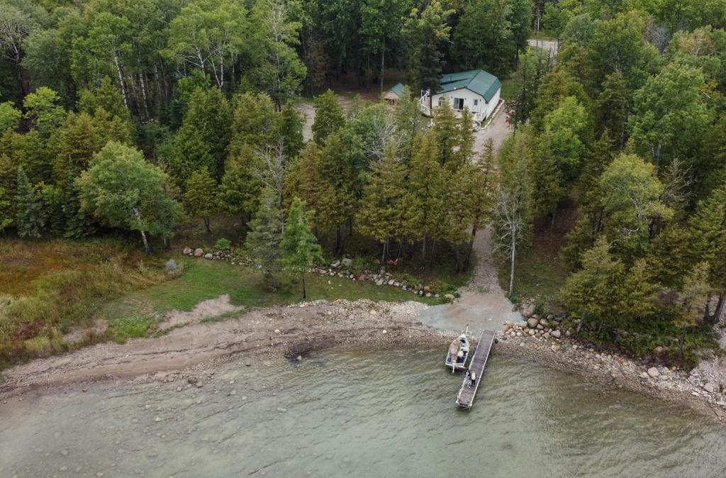 Waterfront 2-BR Cottage Retreat in Manitoulin Island في Kagawong: اطلالة جوية على منزل و قارب في الماء