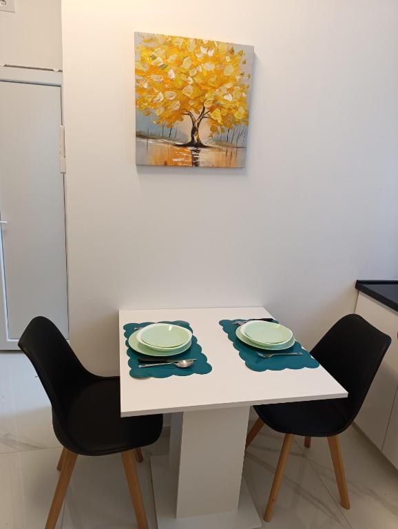 a white table with two chairs and a tree at Studio San in Arandjelovac