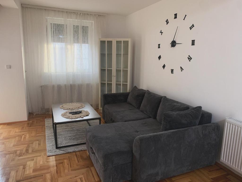 ein Wohnzimmer mit einer Couch und einer Uhr an der Wand in der Unterkunft City Comfort Apartment in Vranje