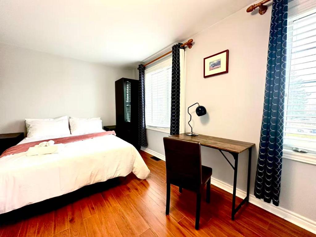 a bedroom with a bed and a desk and windows at Cozy Queen room with Shared Bath near Seneca Finch 404 in Toronto