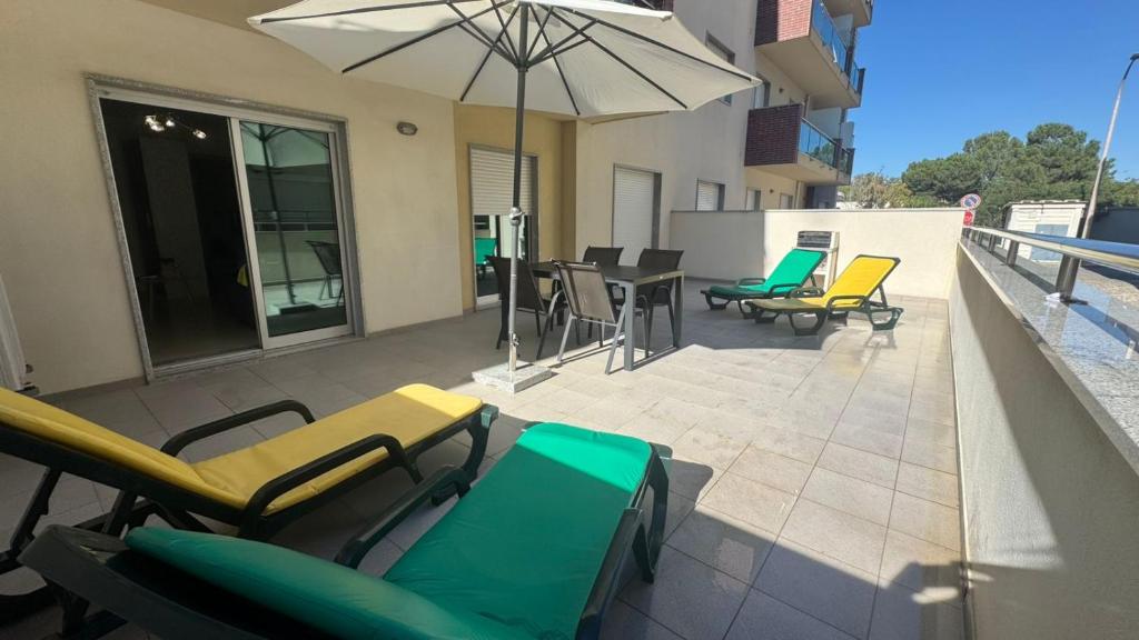 une terrasse avec des chaises, des tables et un parasol dans l'établissement Laguna mar beach house, à Monte Gordo