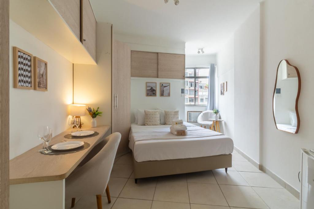 a small bedroom with a bed and a desk and a table at 4 minutos da Praia de Copacabana - NSC803 in Rio de Janeiro