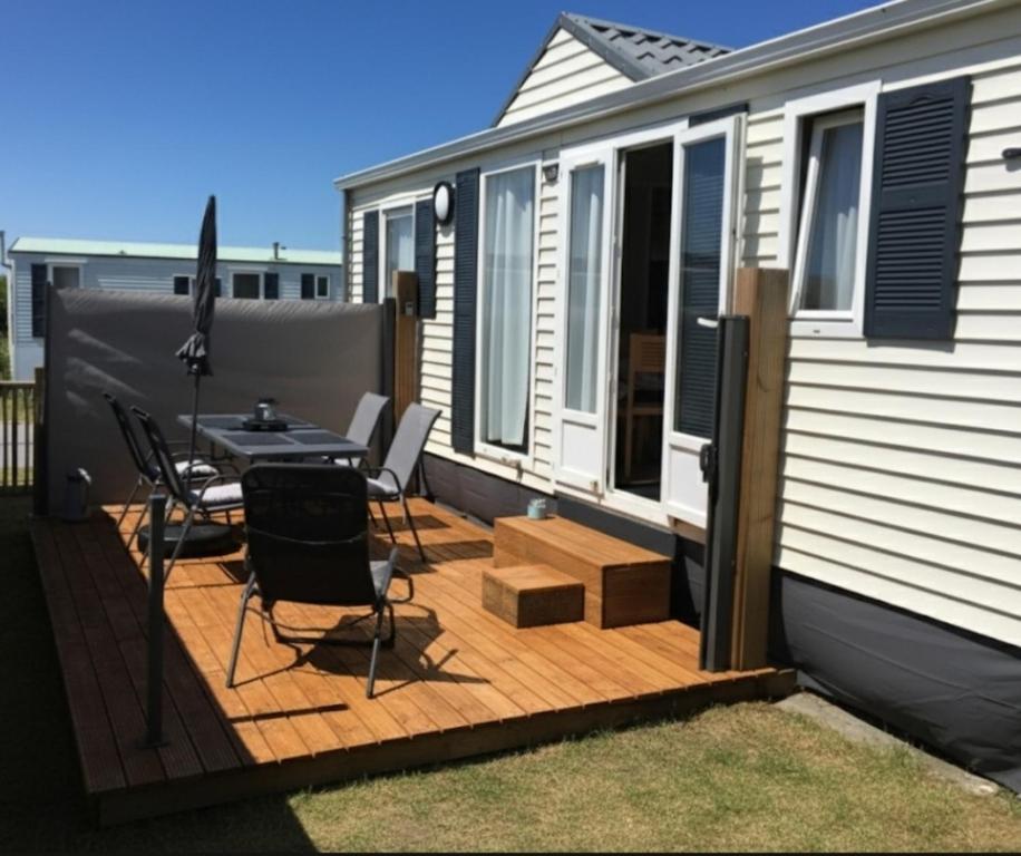 eine Terrasse mit einem Tisch und Stühlen in einem winzigen Haus in der Unterkunft NORDSEE GLAMPING MobilheimChalet 2154 in Bredene