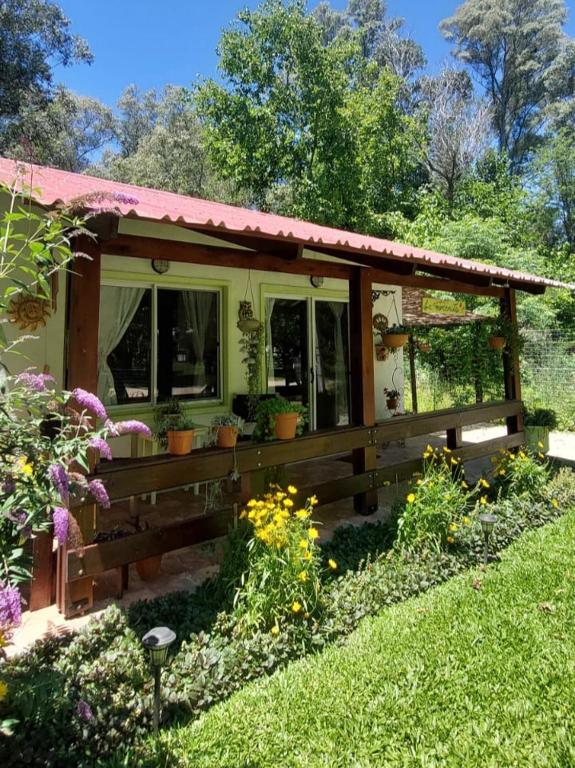 a small house with a porch and some flowers at "La morenita", acogedora cabaña para dos in Santa Ana