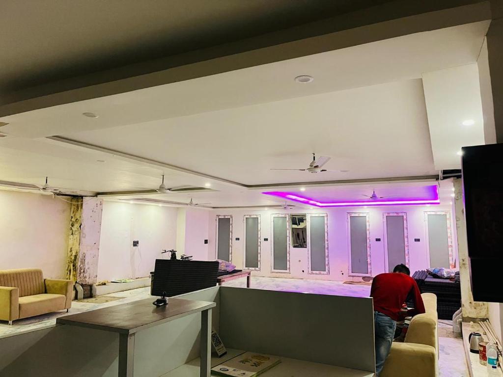 AyodhyaHotel Kaushalya的一个男人站在一间亮着紫色灯光的客厅里。