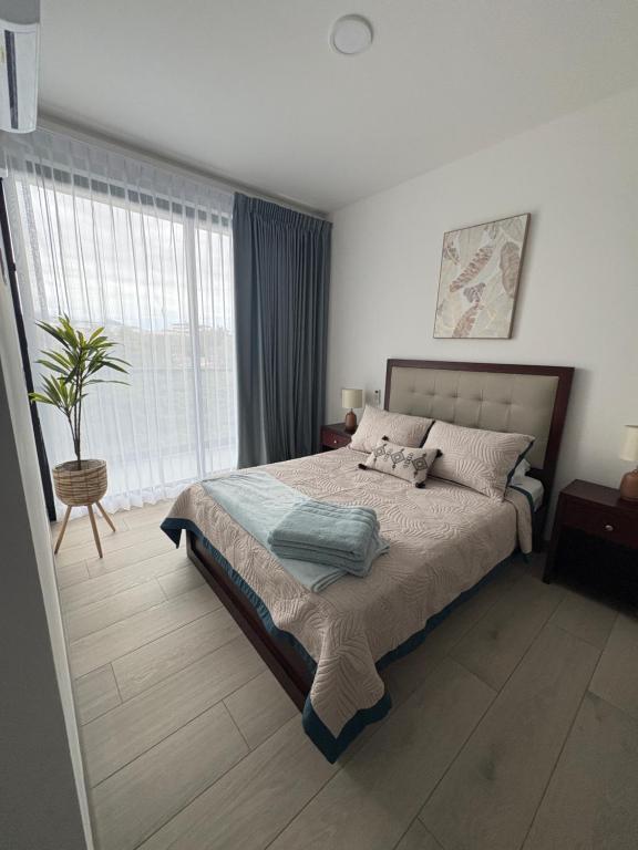 a bedroom with a bed and a large window at Modern Condo in Núcleo La Sabana with Pool in San José