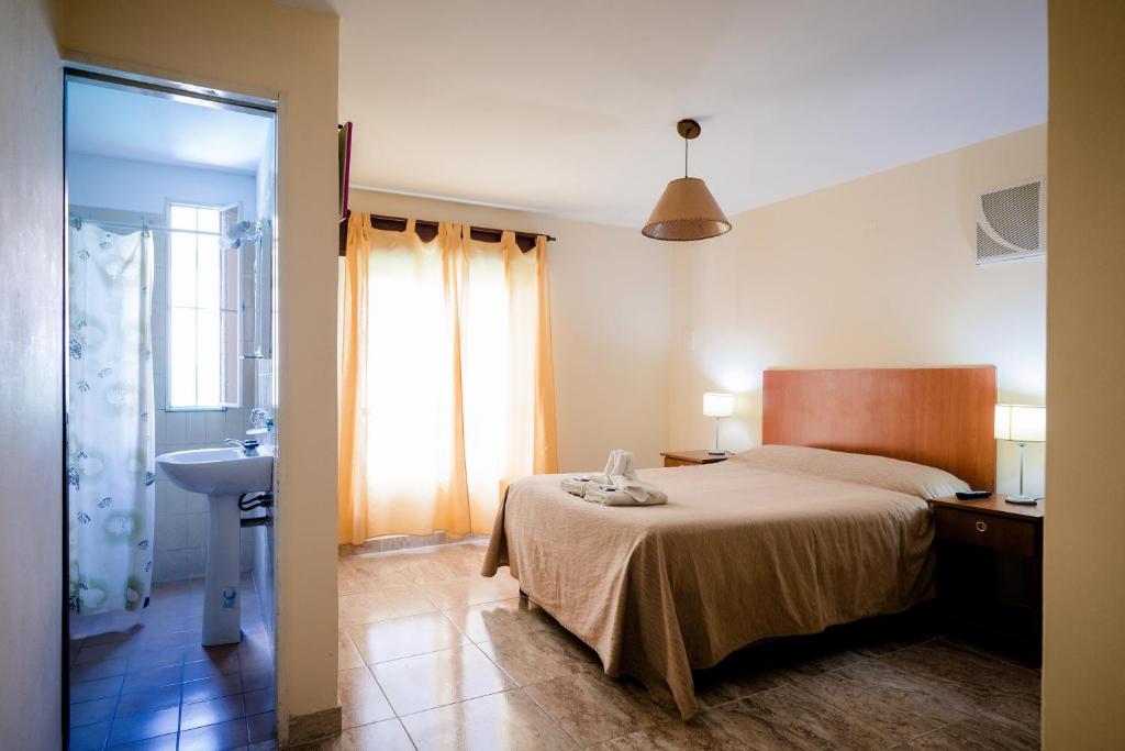 een slaapkamer met een bed en een badkamer met een wastafel bij Carlos Paz Departamentos in Villa Carlos Paz