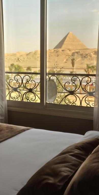 a bedroom with a view of the pyramids from a window at Pyramids & Grand Museum Apartment in Giza