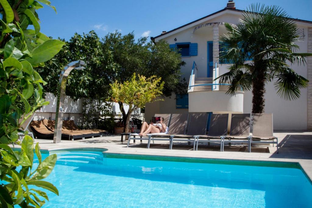 a woman sitting on a bench next to a swimming pool at Apartments Villa Pina in Vodice