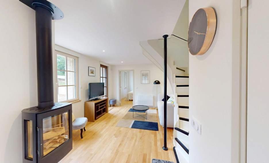 Una sala de estar con chimenea y televisión. en Au bord de l'Odon, en Louvigny