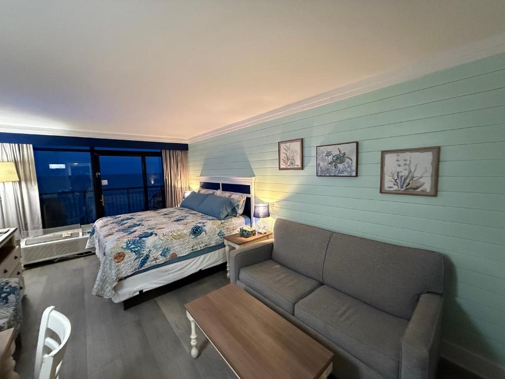 ein Schlafzimmer mit einem Bett und einem Sofa sowie einem Bett und einem Fenster in der Unterkunft Grande Cayman 1BR Penthouse Patio Oceanfront Views in Myrtle Beach