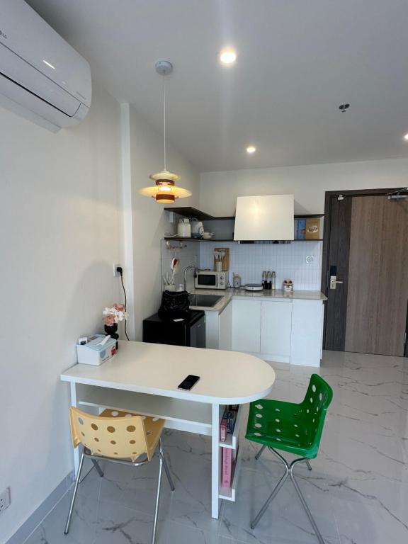 una cucina con tavolo bianco e due sedie verdi di Căn nhà nhỏ a Long Bình