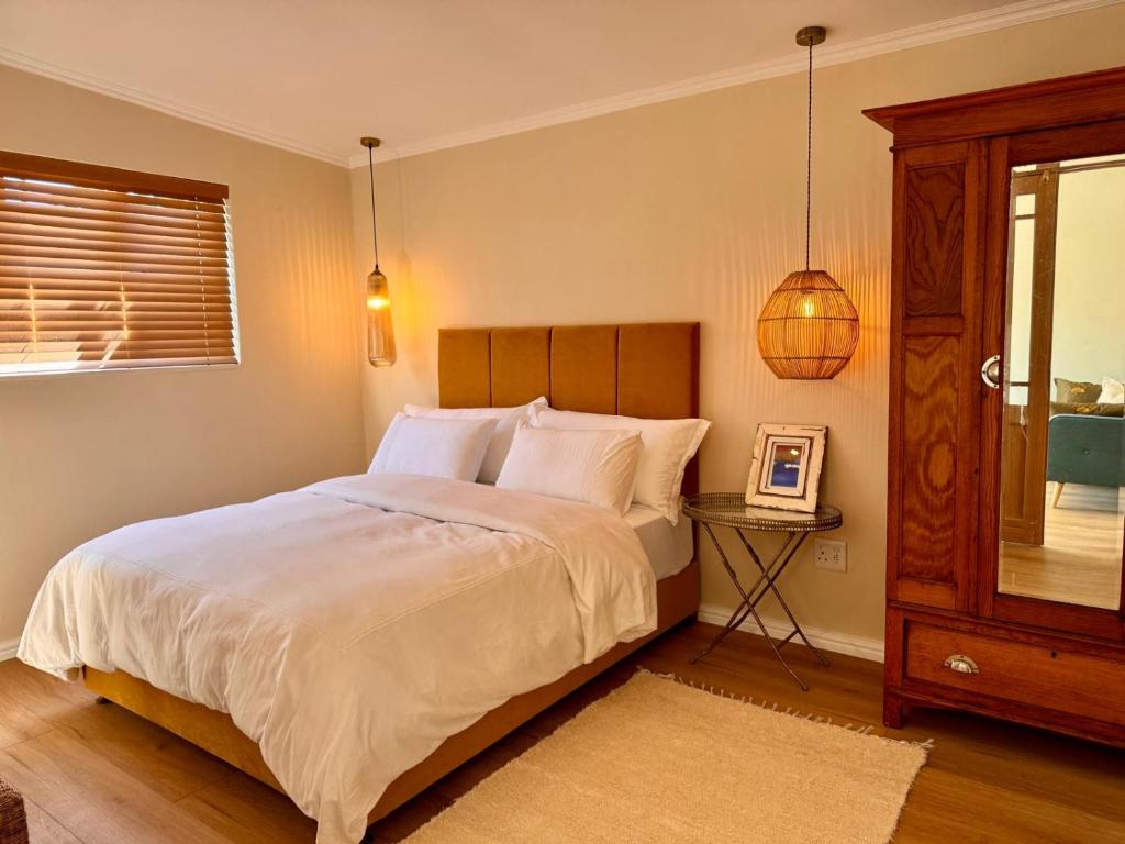 a bedroom with a bed and a table and a window at Mimosa Cottage in Cape Town
