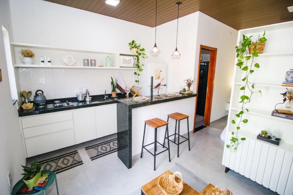 a kitchen with white cabinets and a black counter top at Flat Aconchego dos Pássaros in Bonito