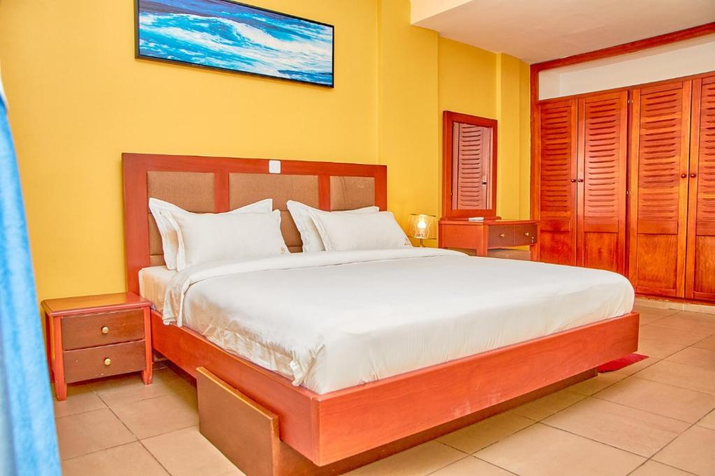 Résidence Belmann في دوالا: غرفة نوم بسرير كبير وبجدران صفراء