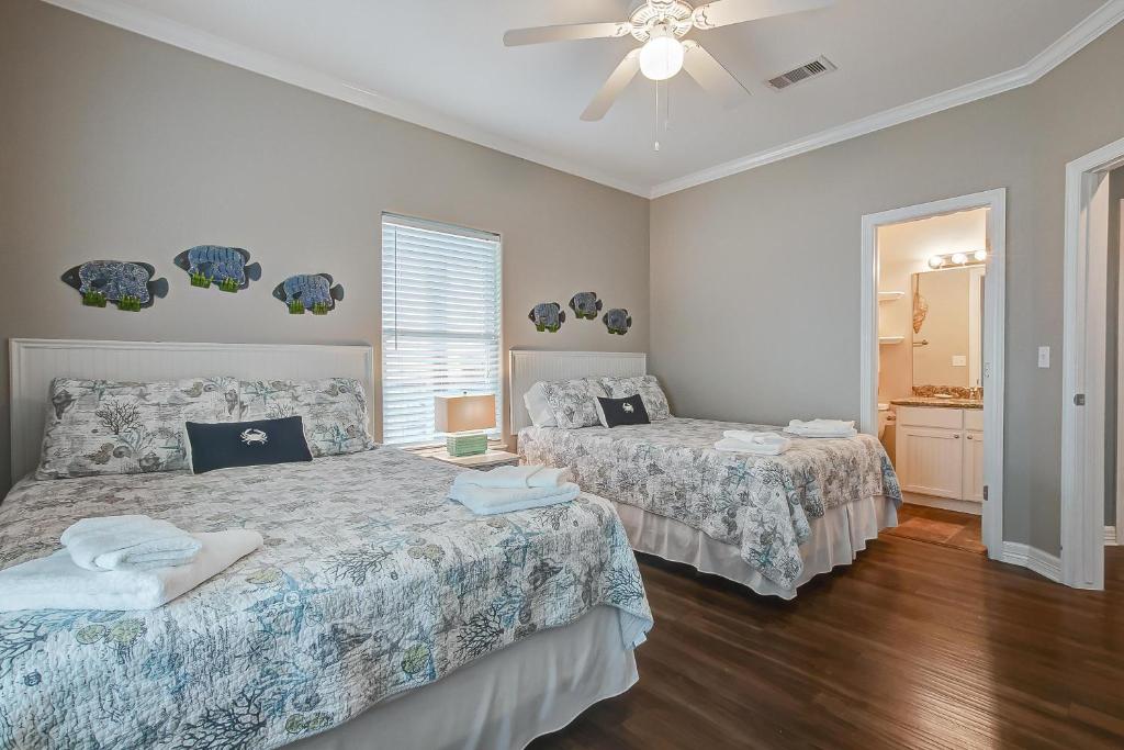 ein Schlafzimmer mit zwei Betten und einem Deckenventilator in der Unterkunft Crystal Moon in Crystal Beach