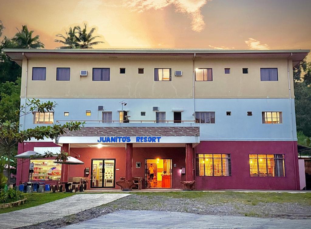 TangalanJuanito's Resort的一座白色的大建筑,前面设有一间餐厅