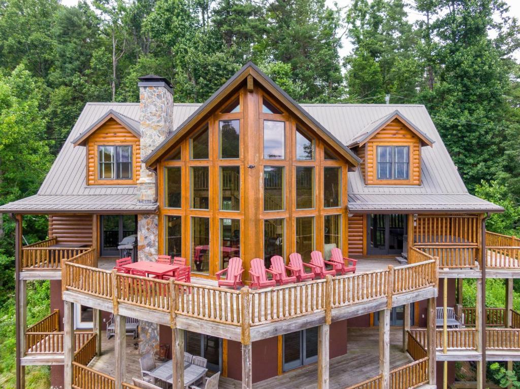 eine Blockhütte mit einer Rundumterrasse mit roten Stühlen in der Unterkunft Hidden Ridge in Boone