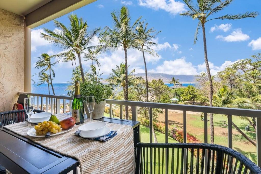 a table on a balcony with a view of the ocean at Menehune Shores 403 · MHS 403 Remodeled BeachFront 2BD Getaway in Kihei