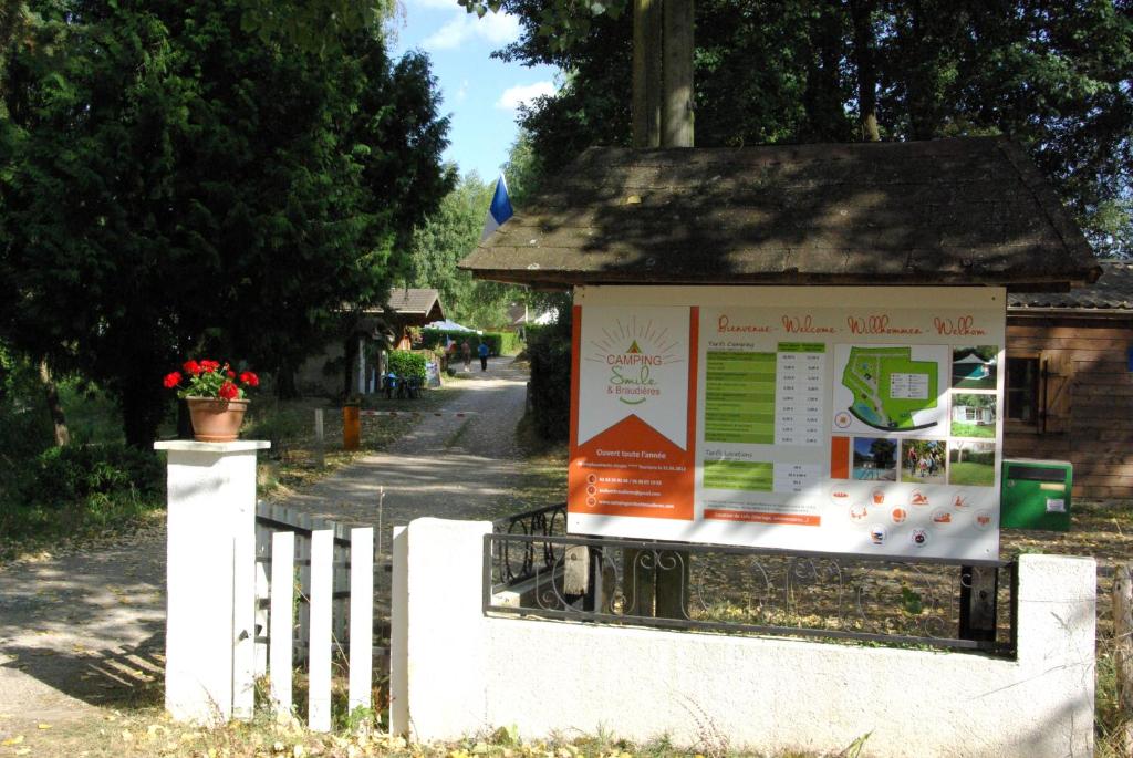 un cartello su una recinzione vicino a una strada di Camping Smile & Braudieres a Mézières-sous-Lavardin