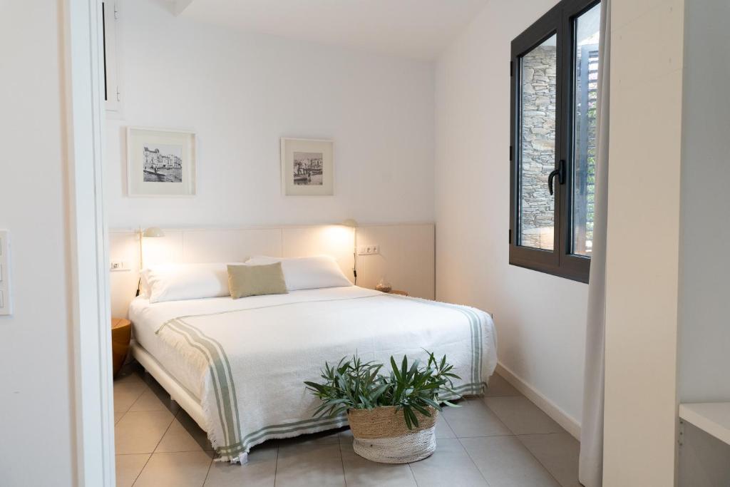 1 dormitorio con cama blanca y maceta en Gaia Apartments & Lofts Cadaqués, en Cadaqués
