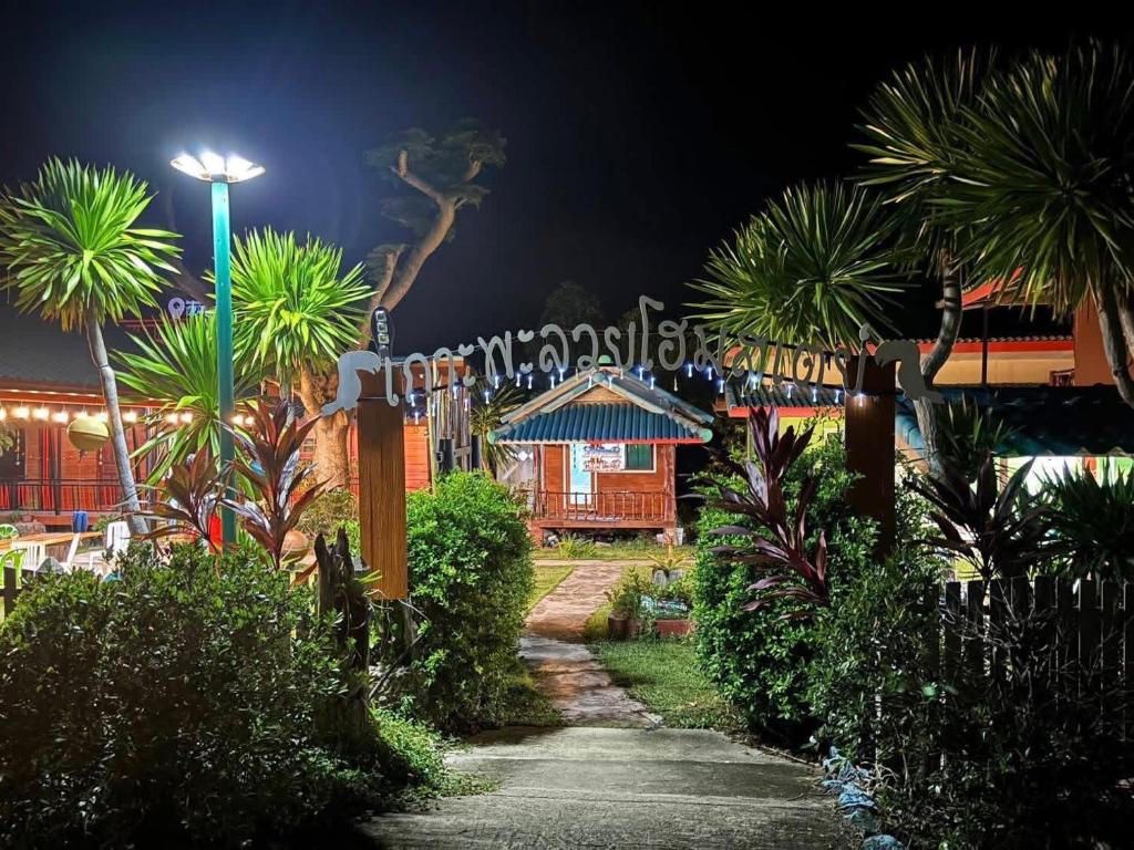 a garden with palm trees and a house at night at PhaluaiHomestay พะลวยโฮมสเตย์ บ้านไม้ in Koh Phaluai