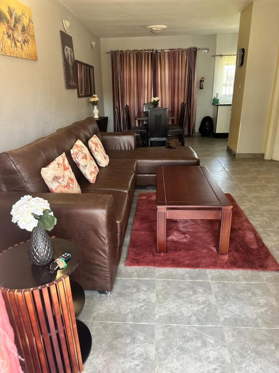a living room with a brown leather couch and a table at Hatfield - Staylax Manor 3 in Harare