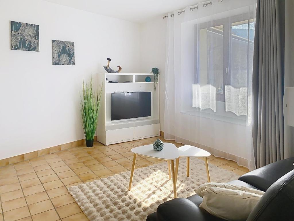 a living room with a couch and a tv at Les Cerisiers in Saint-Étienne-de-Crossey