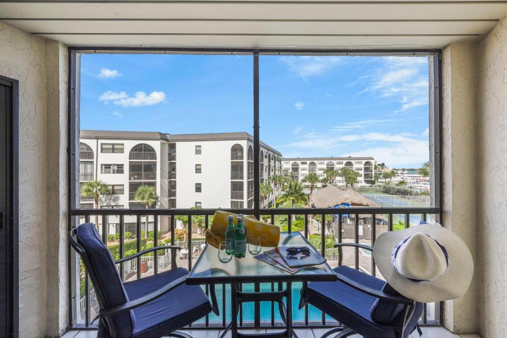 a balcony with a table and chairs and a large window at Pleasant condo with spectacular views, pools and spas in Marco Island