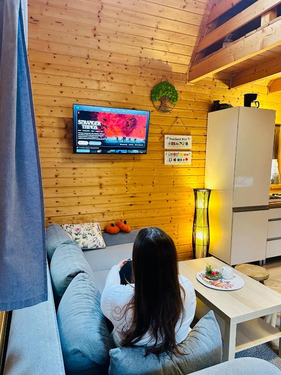 戈鲁别Dolina Bella - ogrzewany domek z balią, sauną i kominkiem w sercu Kaszub的坐在沙发上看电视的女人