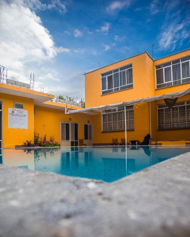 a yellow house with a swimming pool in front of it at Casa de los Abuelos in Itzamatitlán