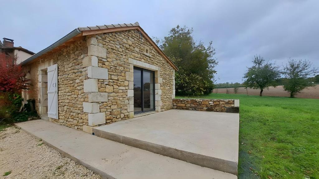 a small stone building with a large patio at Spacieuse maison de vacances in Sorges