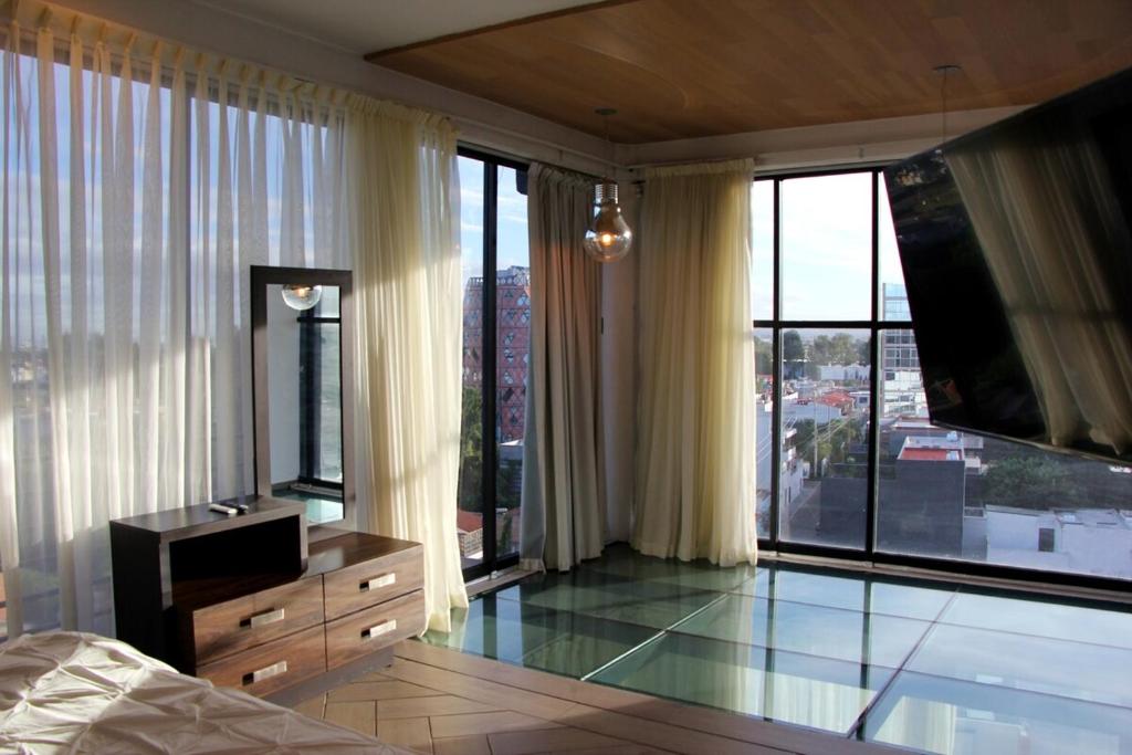 a bedroom with a dresser and glass floors and windows at Penthouse with Glass Floor and Volcano View in Cholula