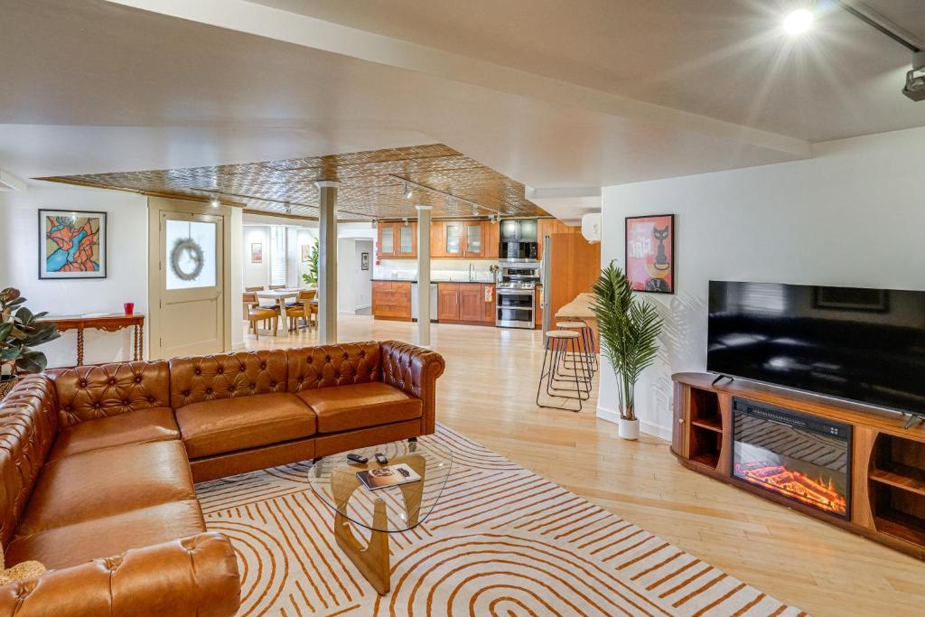 a living room with a brown couch and a television at Walk to Athens Riverfront Park! Modern-Retro Apt in Athens