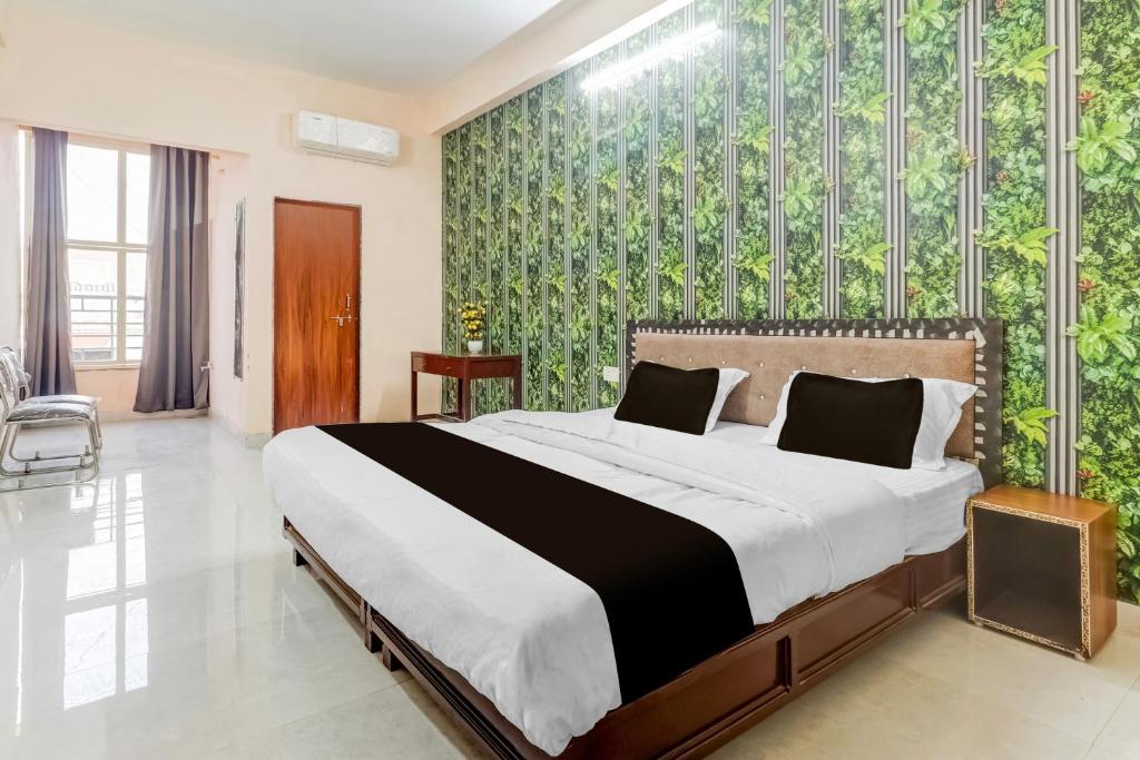 Un dormitorio con una cama grande y una pared verde. en Hotel O by OYO Swastik inn, en Gwalior