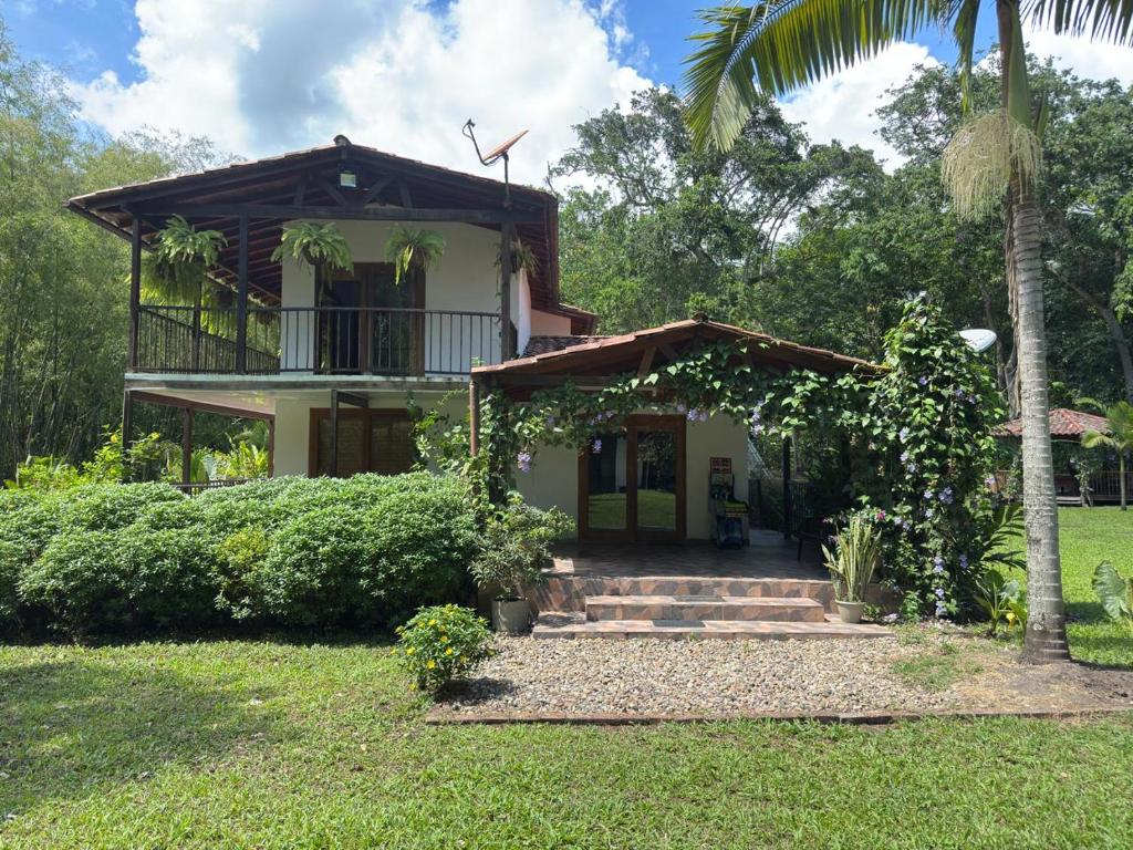 uma casa com uma varanda e uma palmeira em Hermosa CasaQuinta Con Piscina Privada. em Villeta