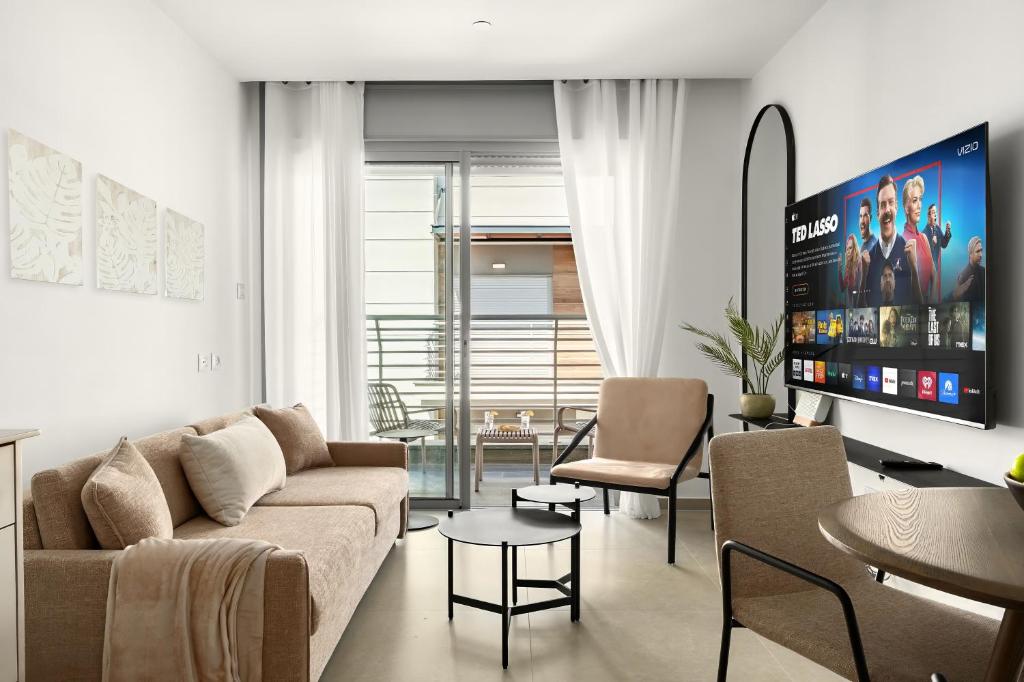 un salon avec un canapé et une télévision dans l'établissement Modern Eilat Escape with Heated Pool, à Eilat