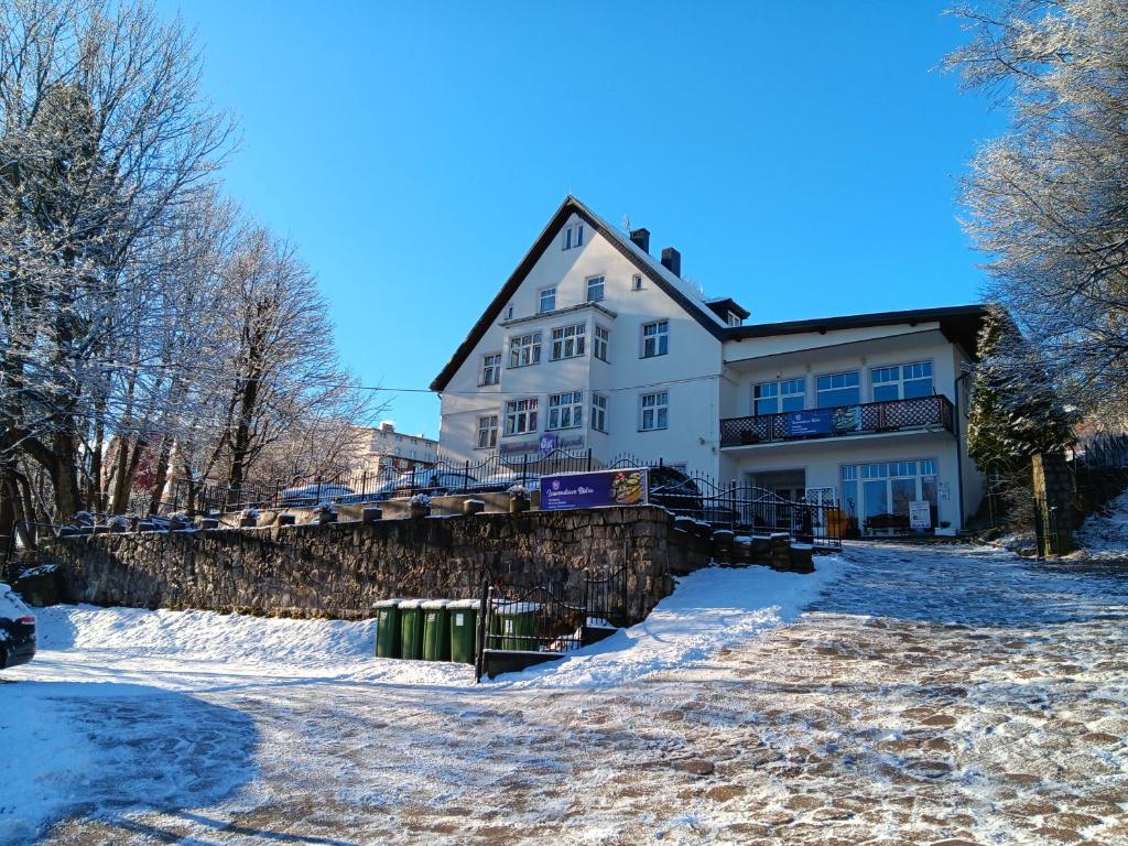 ein großes weißes Haus mit einer Steinmauer im Schnee in der Unterkunft Lawendowy Dworek in Karpacz