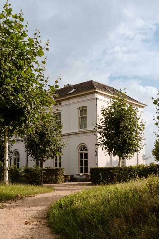 a white house with two trees in front of it at Boutique Hotel De Witte Dame in Abcoude