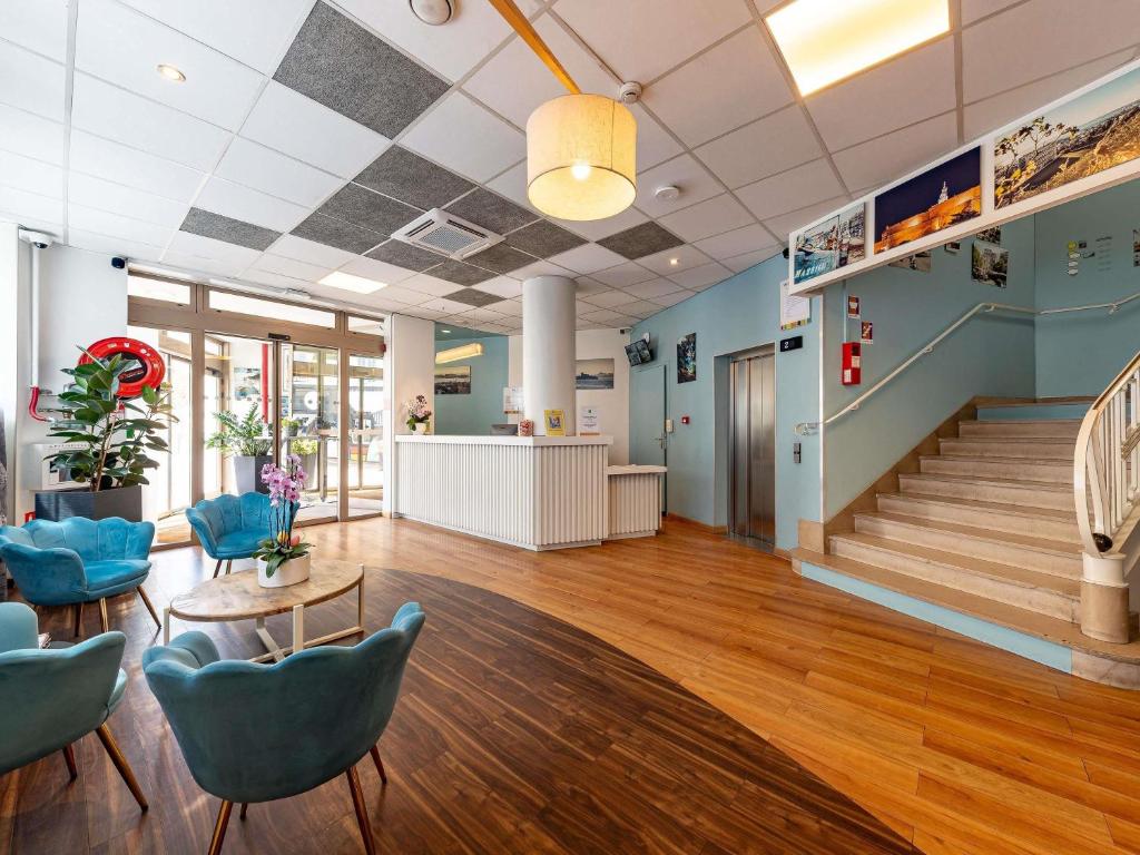 um átrio com uma escada e cadeiras azuis em ibis Styles Marseille Centre Prado Place Castellane em Marselha